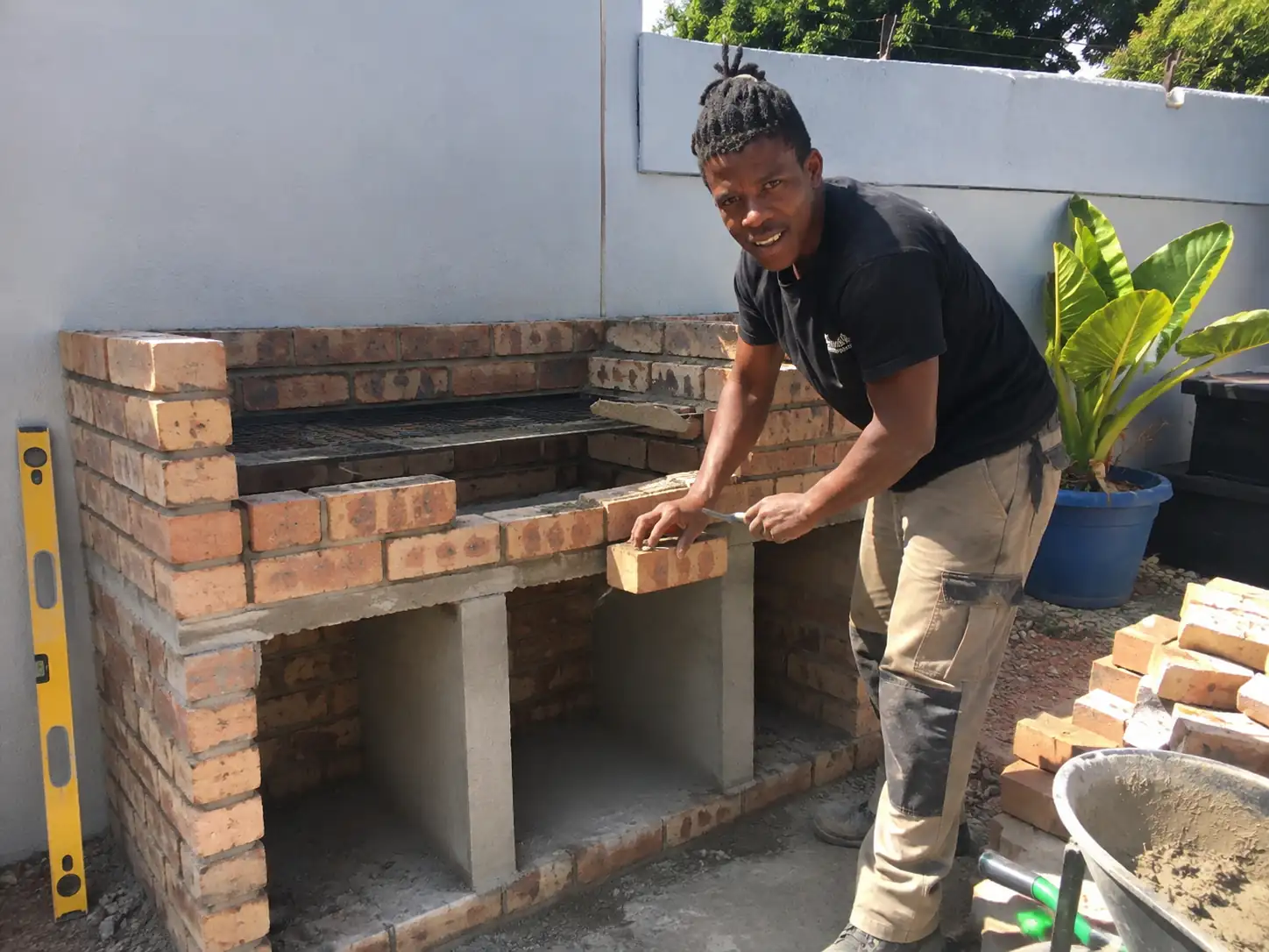 Bricklayer laying face brick on a new built-in braai in an Edenvale garden